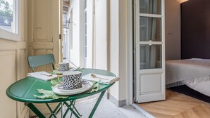 Ein Zimmer mit einem Bett, einem Tisch mit zwei Tassen mit Leopardenmuster, einem Stuhl und einer Tür, die nach draußen führt.