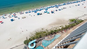 Una spiaggia con numerosi ombrelloni e lettini, una zona piscina e una vista libera sull'oceano.