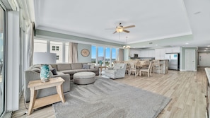 A spacious living area with a sofa, ottoman, and dining set.