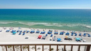 A beach with numerous umbrellas and sun loungers, a sandy shore, and the ocean in the background. - Beachfront 4BR Corner Unit!  Water Slide!! (Gulf Shores)