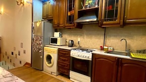 Une cuisine compacte avec des meubles en bois, un lave-linge, un four à micro-ondes et une cuisinière.
