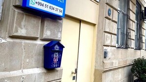 Une enseigne indiquant la présence d’une auberge de jeunesse, avec un numéro de téléphone, sur la façade d’un immeuble de couleur beige.
