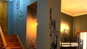 Une pièce avec un lit superposé, un escalier et un mur orné d’une fresque représentant la Statue de la Liberté.