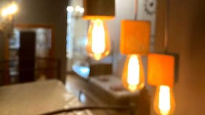 Une chambre comprenant un lit, une table de chevet et une lampe avec un pied carré et un abat-jour cylindrique.