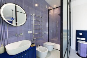 Un bagno moderno con uno specchio ovale grande, una vasca freestanding, un bidet e una cabina doccia in vetro.