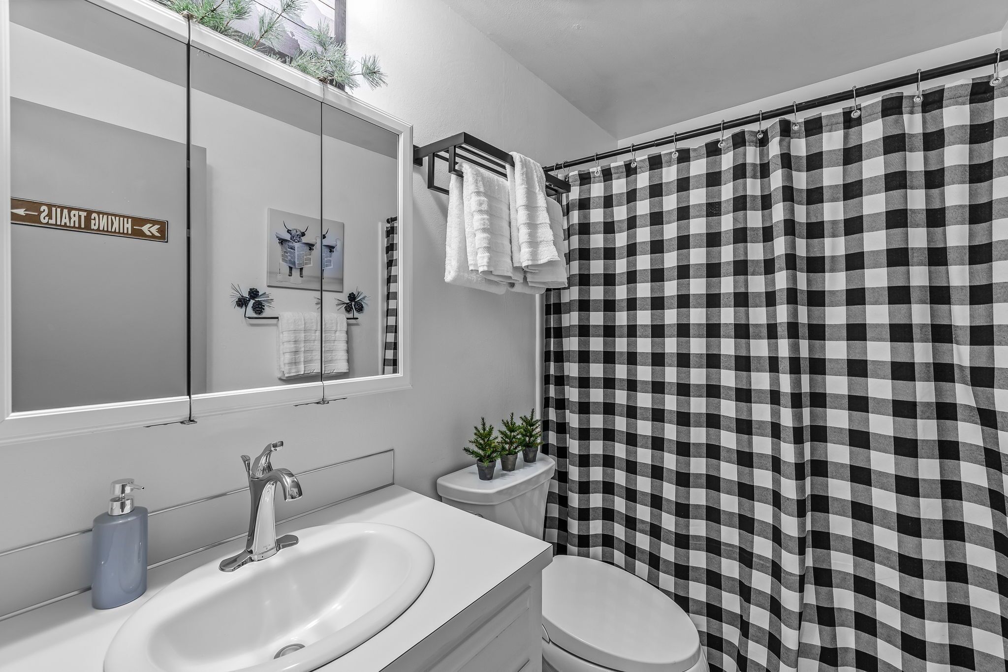 Un bagno con un lavandino bianco, un water e una tenda da doccia a scacchi bianchi e neri.