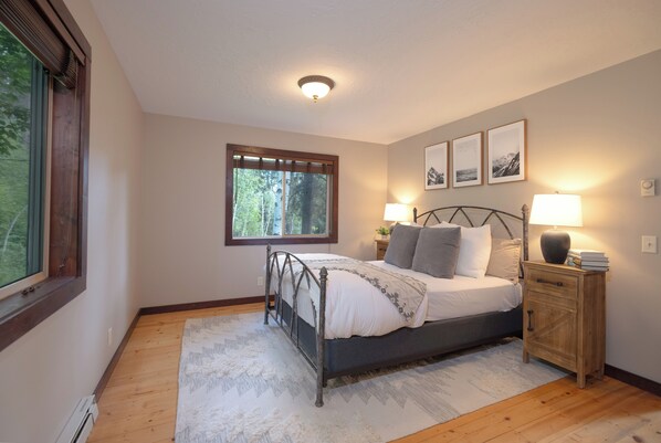A bedroom with a bed, nightstand, and window. - Forget Me Not Cabin in the Woods w/ Wood Stove, Wifi, W/D, Pet Friendly! (Victor)