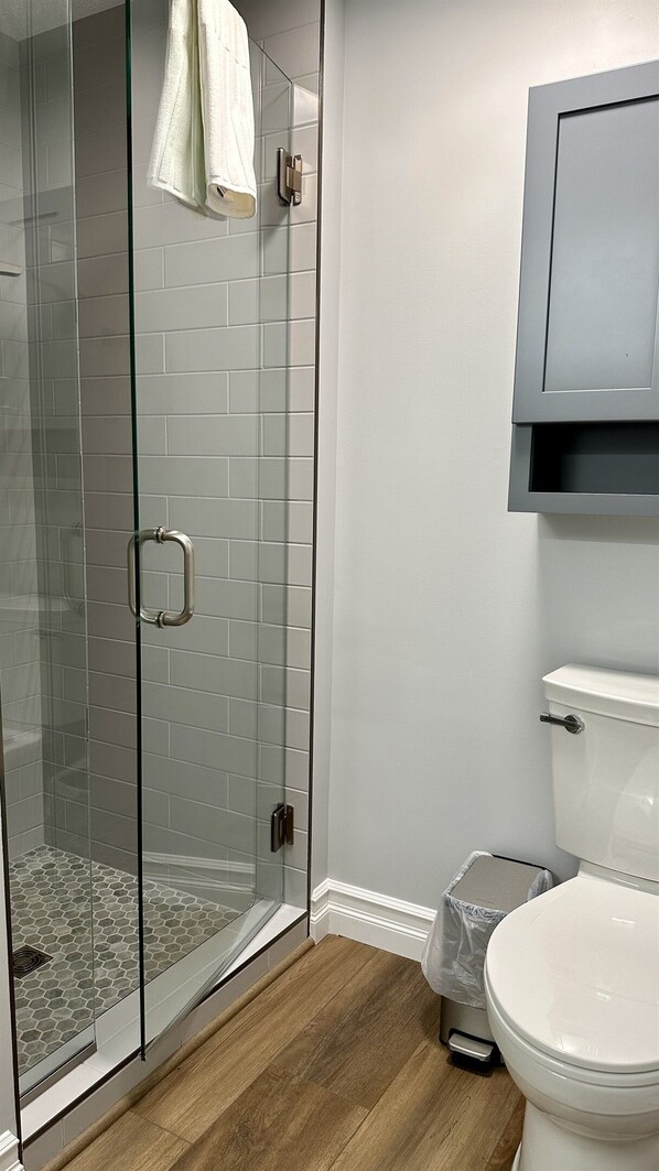 A bathroom with a glass shower enclosure, a toilet, and a cabinet. - Empire Beach House - Lake Michigan cottage with firepit, grill & furnished deck (Empire)