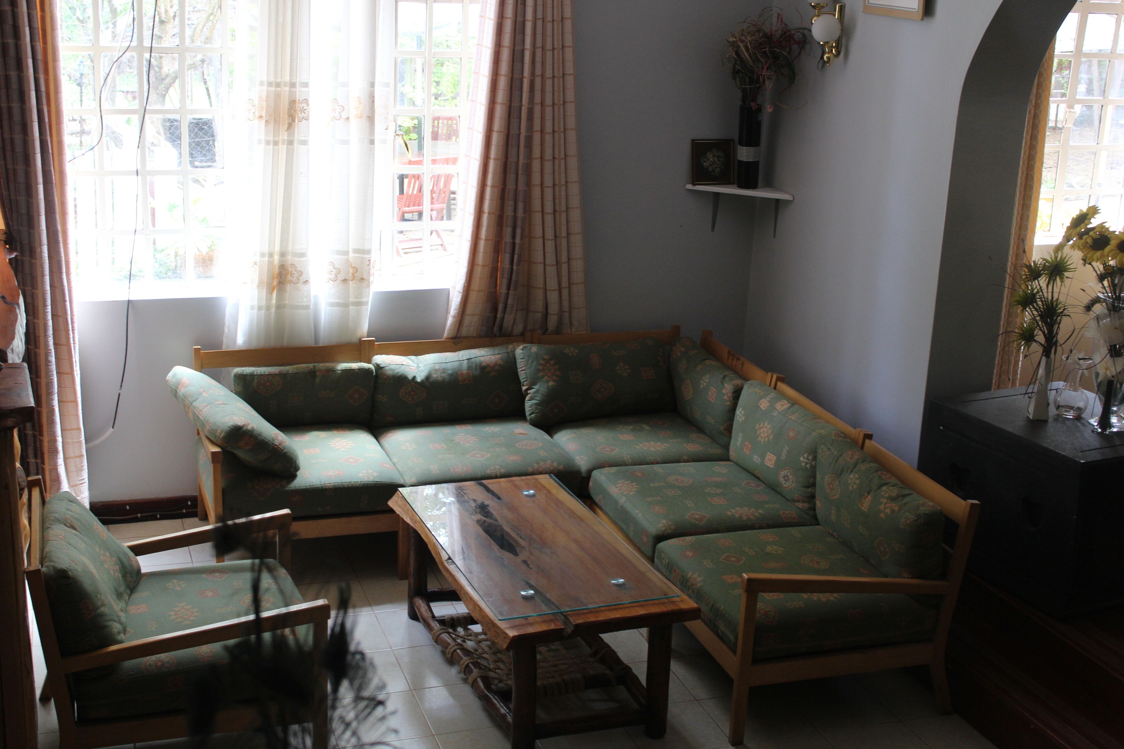 A living room with a green sofa set, a wooden coffee table, and a chair.