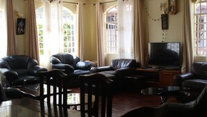 A living room with leather sofas, a glass coffee table, and a flat-screen TV. - Tranquil homestays (Naro Moru)