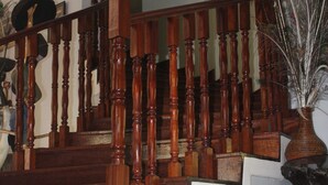 A wooden staircase with a handrail and a vase with dried plants at the bottom. - Tranquil homestays (Naro Moru)