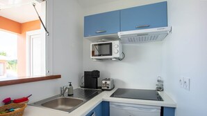 Een kleine keuken met een spoelbak, een broodrooster, een magnetron en een koffiezetapparaat.