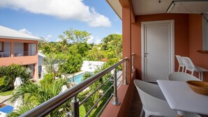 Een balkon met een metalen hekwerk, witte stoelen en een tafel. Er is een deur en een bord met de naam van het hotel 'Guzman de la Palma'.