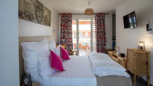 Een hotelkamer met een bed, een televisie, een bureau en een raam met gordijnen.