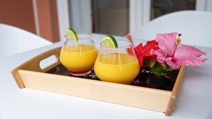 Un plateau avec deux verres de jus d’orange et une fleur d’hibiscus.