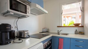 Une cuisine compacte équipée d’un four à micro-ondes, d’un grille-pain, d’une machine à café et d’un lave-vaisselle.