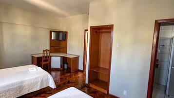 Habitación de hotel con dos camas, un escritorio, una silla, un televisor y un armario.