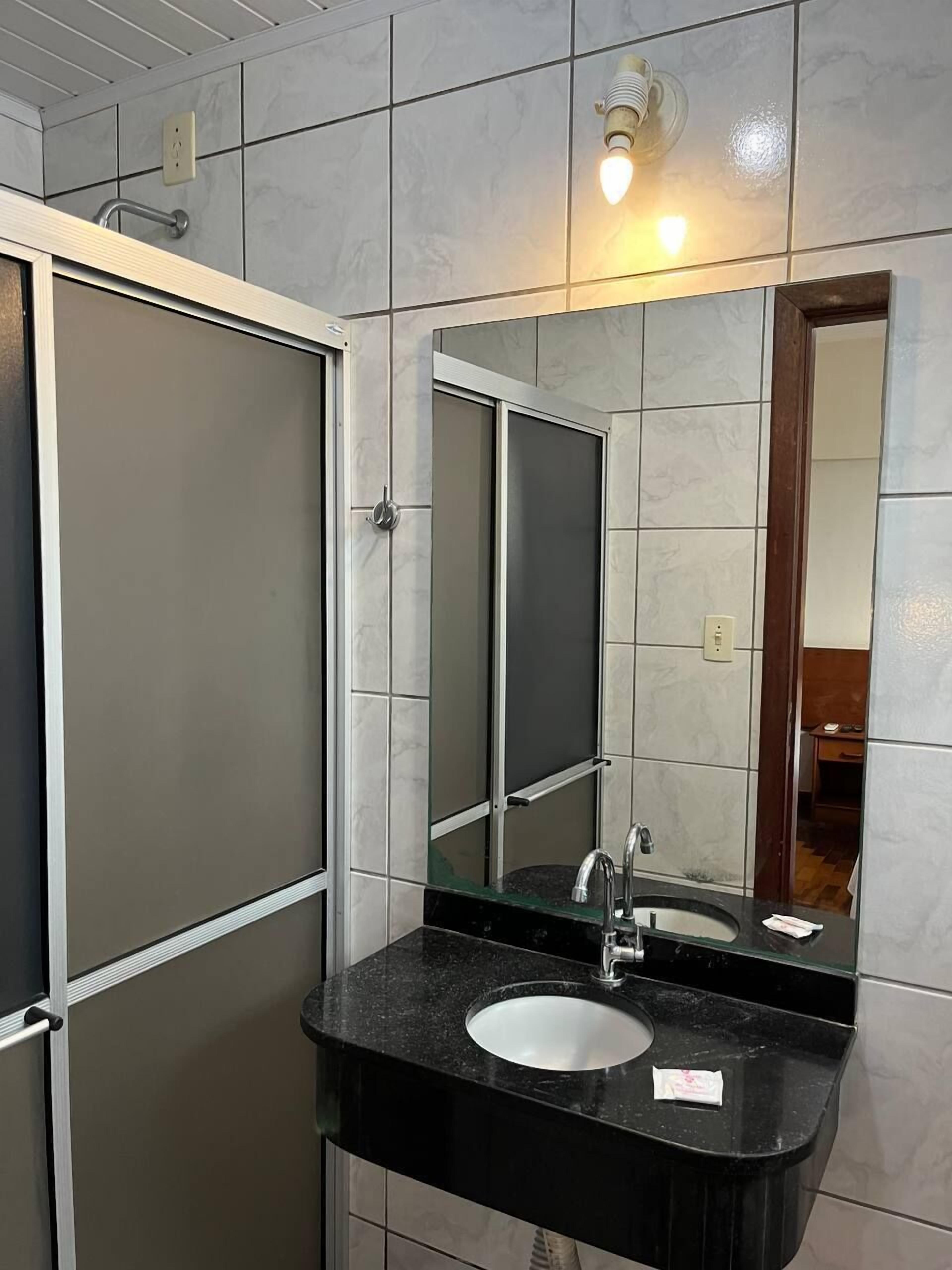 A bathroom with a black sink, a mirror, and a shower door.