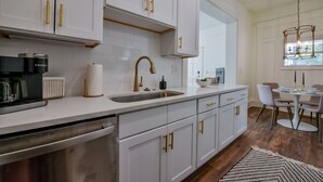 Uma cozinha moderna com armários brancos, puxadores dourados e eletrodomésticos de aço inoxidável.