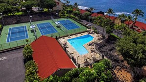 A tennis court, a swimming pool, and a view of the ocean.