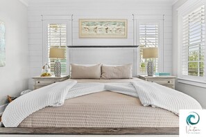 A neatly arranged bedroom with a large bed, two bedside tables with lamps, and a framed picture above the bed.