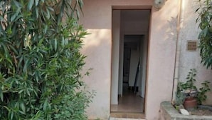 A stone-paved entrance to a building with a small door and a potted plant beside it. - Studio Climatisé Possibilité 4 Adultes/parking Privé (grasse)