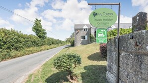 Schild für Ivy Tower Village Private Holiday Cottages mit Hinweis auf Lademöglichkeit für Elektrofahrzeuge.