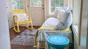 Une chambre confortable avec un lit, un fauteuil à bascule et une fenêtre.