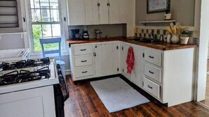 Une cuisine avec des meubles blancs, une cuisinière et une fenêtre.