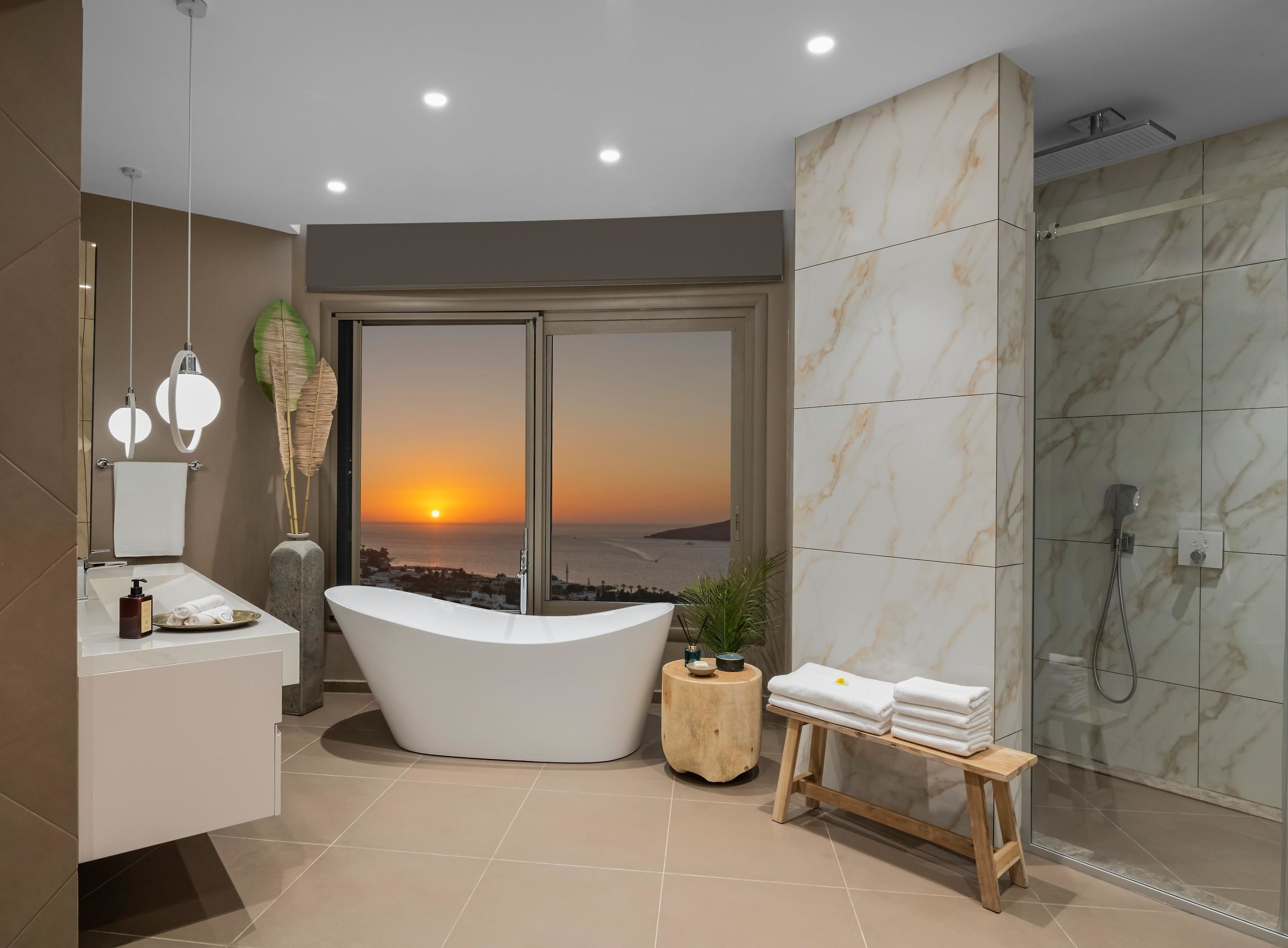 Une salle de bain moderne avec une baignoire sur pieds, un grand miroir et un espace douche offrant une vue sur le coucher de soleil.
