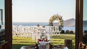 A dining table set for a meal with a view of the ocean and hills in the background. - Ailla Yalıkavak (Bodrum)