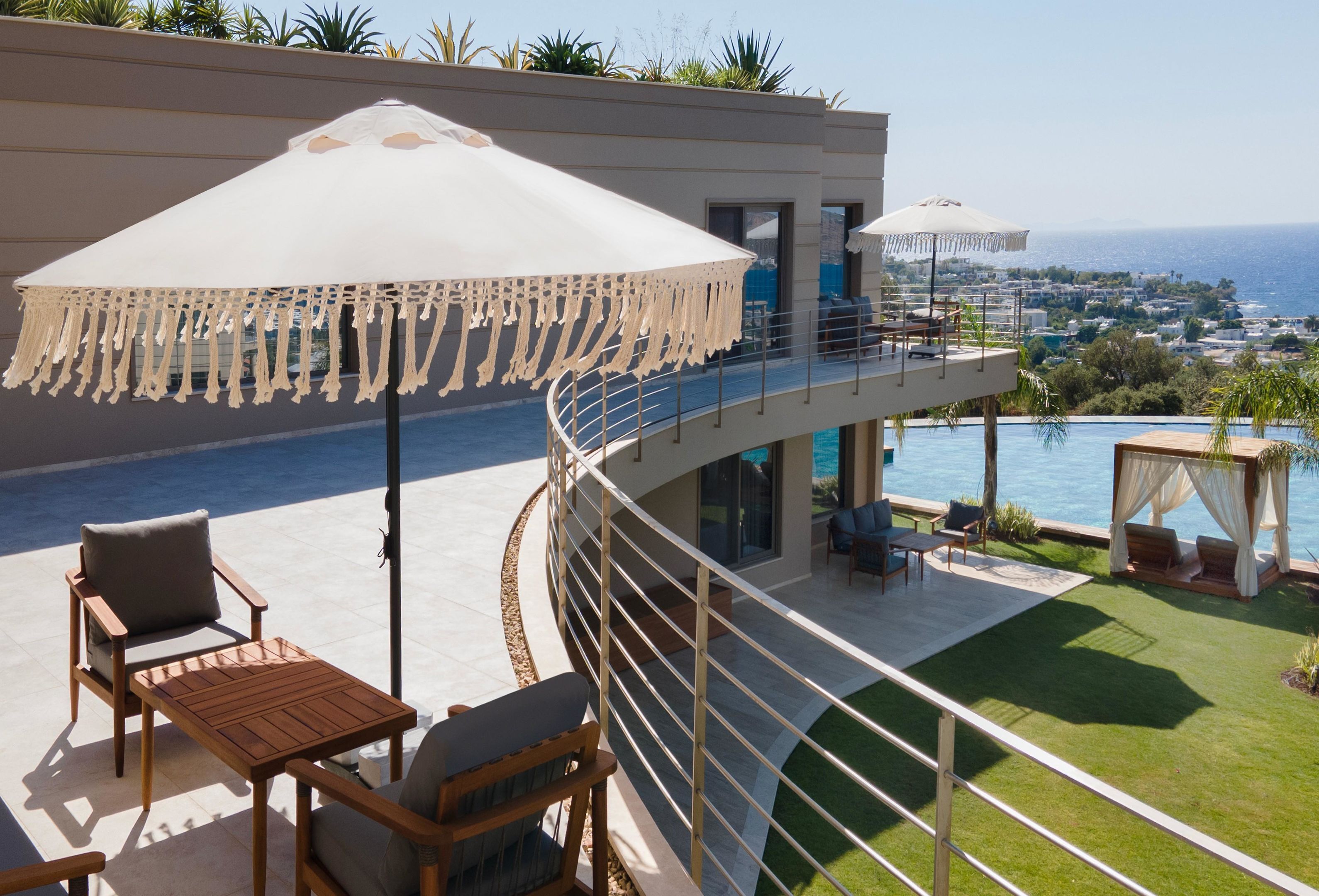 A modern outdoor terrace with a pool, seating area, and a view of the sea.