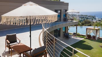 Una terraza moderna al aire libre con piscina, zona de estar y vista al mar.
