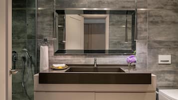 Un baño moderno con un espejo grande, un lavamanos y una ducha.