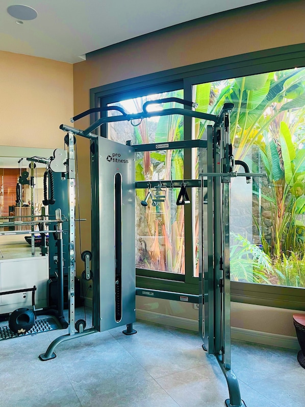 A gym with a pull-up bar, weight machines, and a window with a view of greenery. - Ailla Yalıkavak (Bodrum)