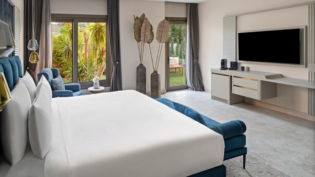 A modern bedroom with a large bed, a desk with a TV, and a view of the outdoors. - Ailla Yalıkavak (Bodrum)