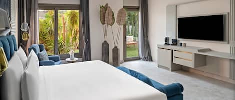 A modern bedroom with a large bed, a desk with a TV, and a view of the outdoors.