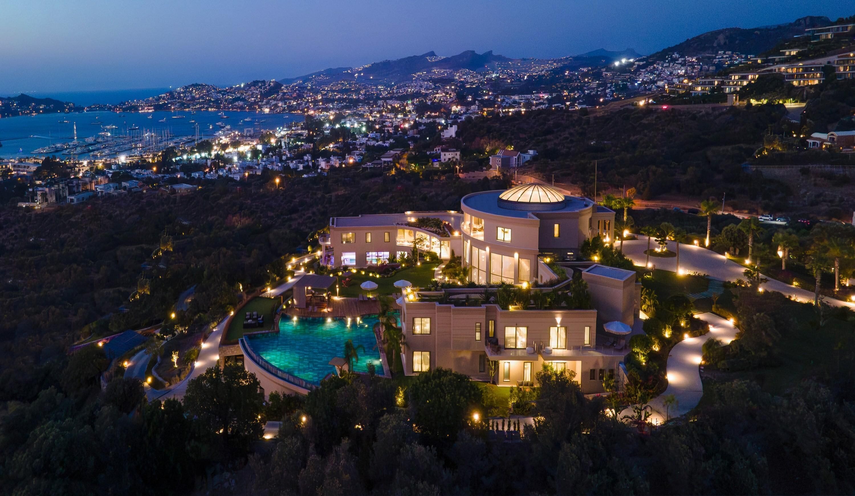 A luxurious resort with a swimming pool, multiple guest rooms, and a scenic view of the coastline.