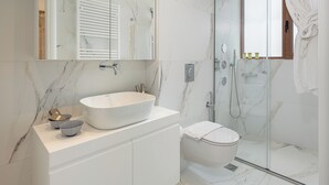 A modern bathroom with a large mirror, a vessel sink, and a glass-enclosed shower. - Elia Seaside Deluxe Apartment (Chania)