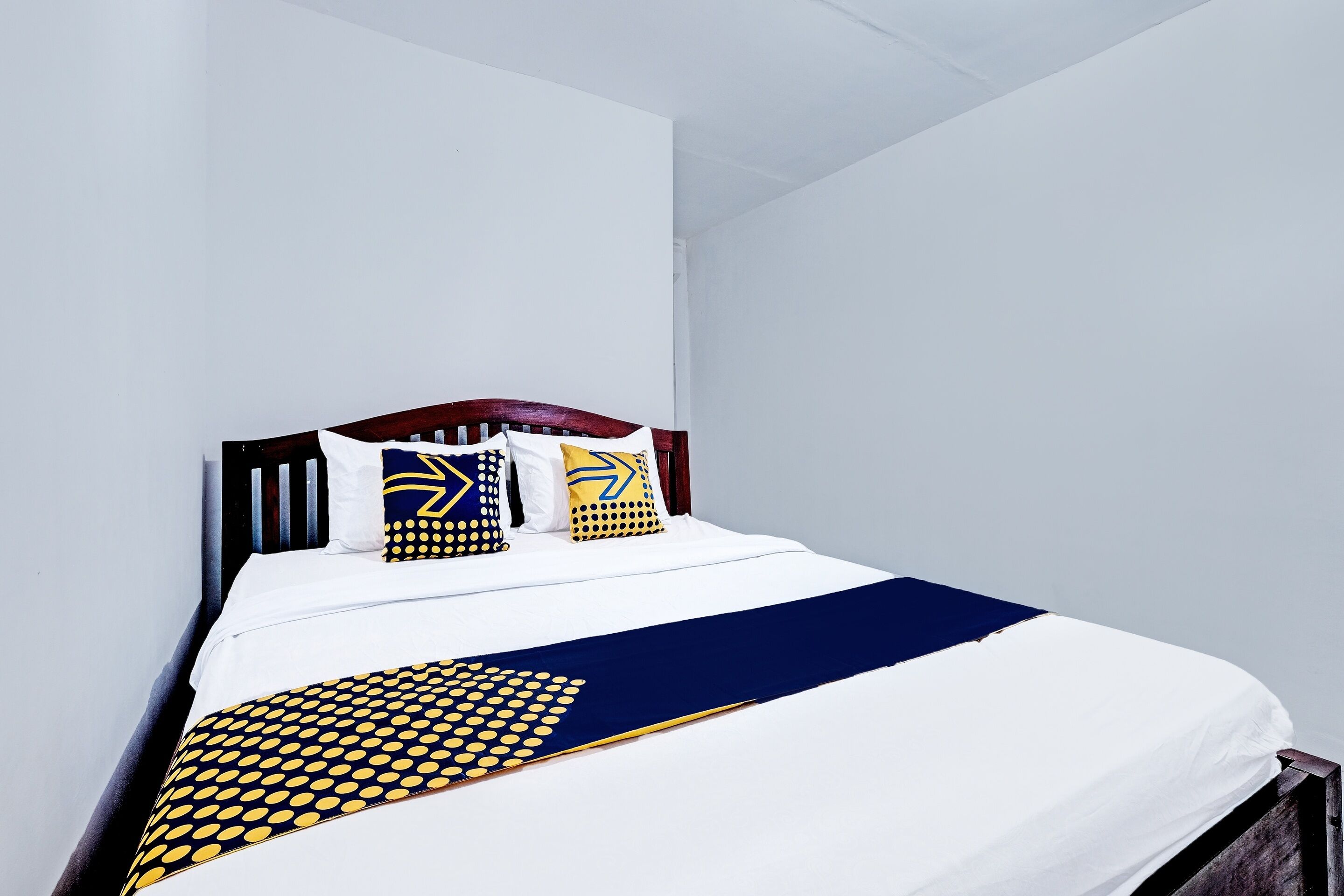 A neatly made bed with a white and navy blue bedspread, featuring a geometric pattern.