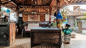 A rustic wooden interior with a large wooden table, a speaker, and a blue hanging pot. - SPOT ON 91916 Joglo Doyong Homestay Syariah (Yogyakarta)