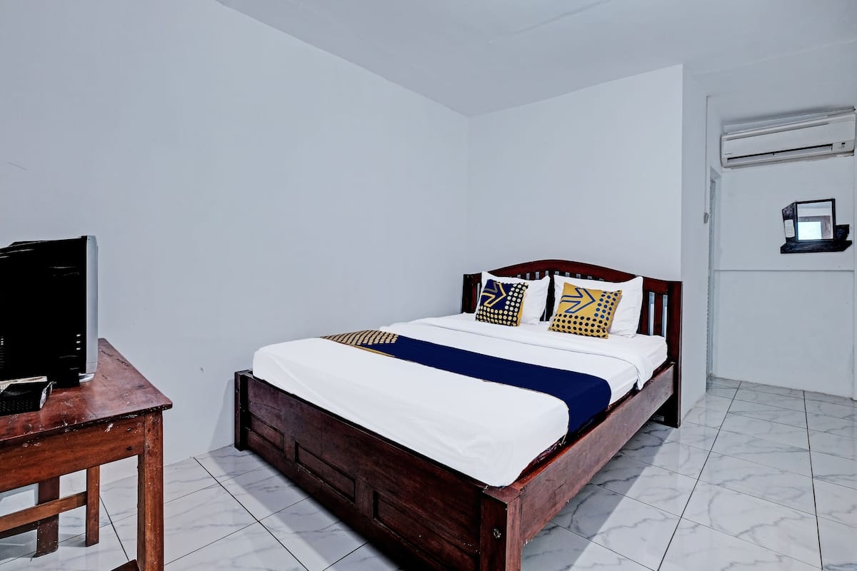 Ein Schlafzimmer mit einem Holzbett, weißen Wänden und einem Fliesenboden.