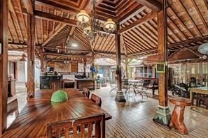 A spacious restaurant with wooden beams, a central dining table, and a ceiling fan. - SPOT ON 91916 Joglo Doyong Homestay Syariah (Yogyakarta)
