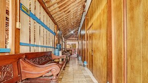 A hallway with wooden benches, a blue sign, and a tiled floor. - SPOT ON 91916 Joglo Doyong Homestay Syariah (Yogyakarta)
