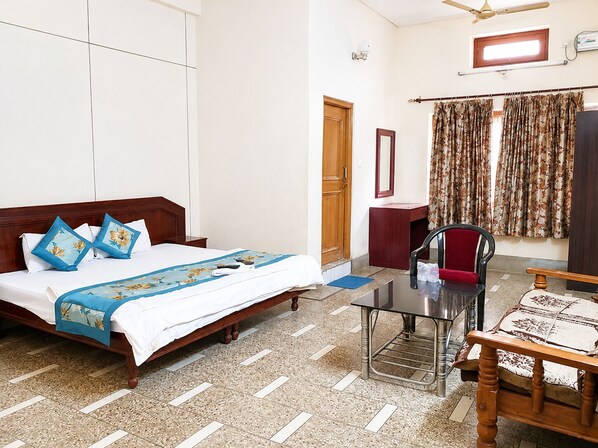 Ein Hotelzimmer mit Bett, Schreibtisch, Stuhl, Spiegel und einem Fenster mit Vorhängen.