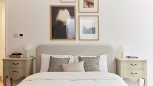 A bedroom with a bed, two bedside tables, and a wall with framed pictures. - The Ravenscourt Park Escape - Bright 2bdr Flat (London)