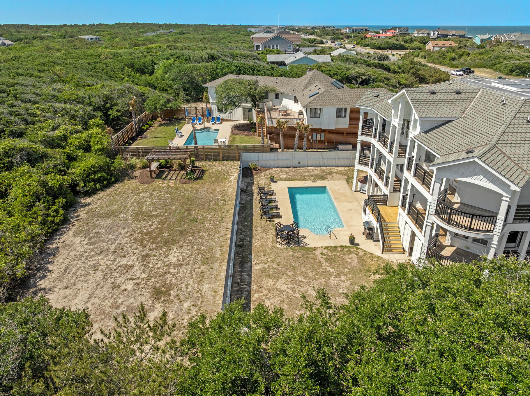 A multi-story building with a swimming pool, outdoor seating, and a view of the surrounding landscape.