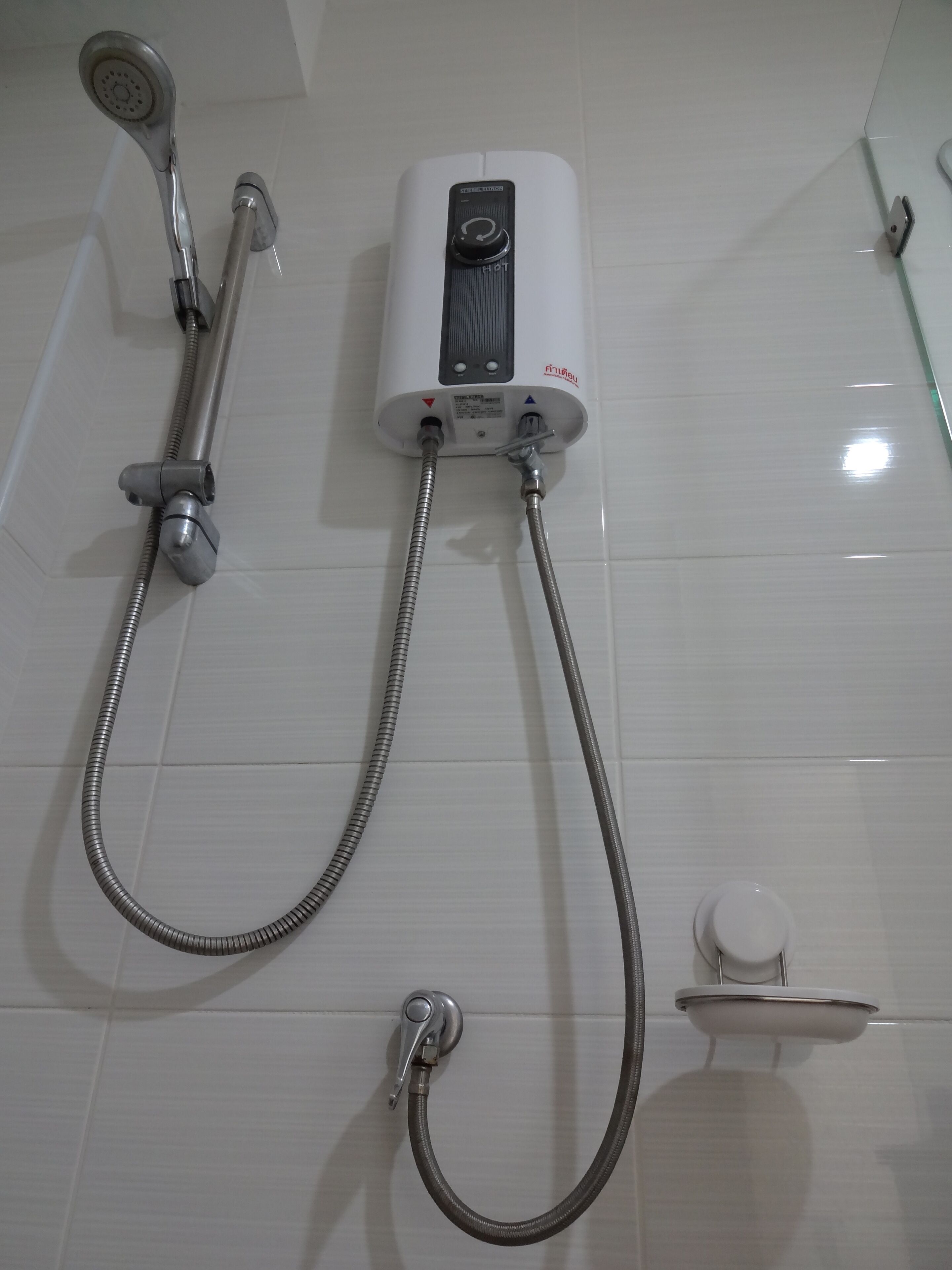 Un ensemble de douche mural comprenant un pommeau de douche à main, un flexible de douche à main et un tuyau de douche à main.