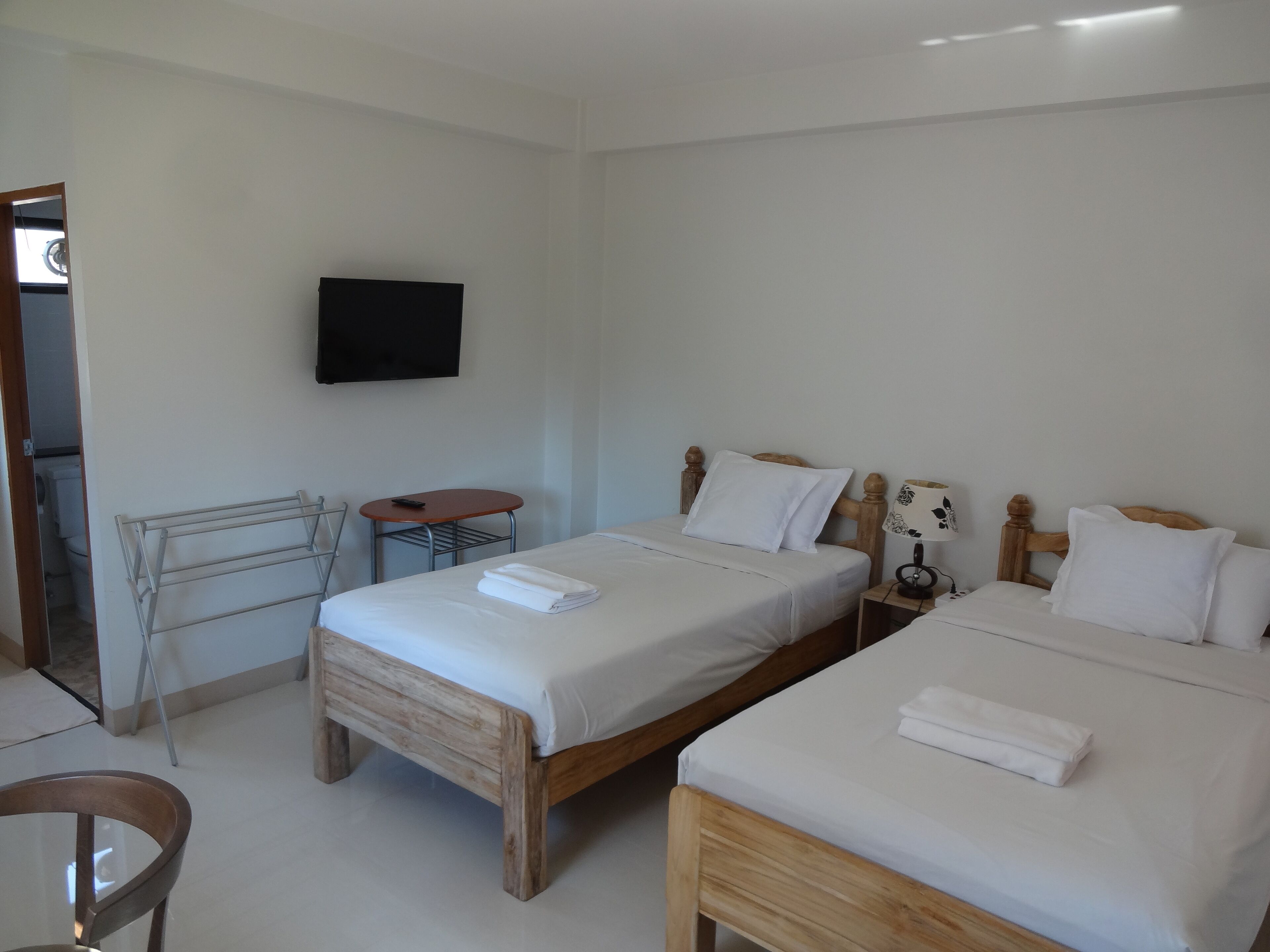 Una habitación de hotel con dos camas, un televisor montado en la pared, una mesita y una silla.