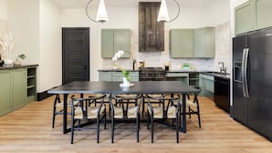 A modern kitchen with a central island, green cabinets, and a black refrigerator. - Stunning, Designer Historic Home | Heated Pool (New Orleans)